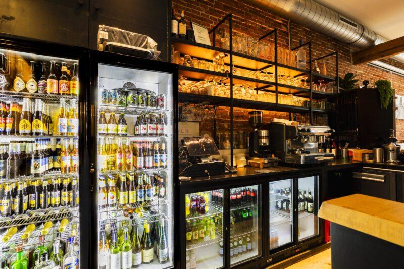 Foto van een horecagelegenheid ter promotie van een nieuw cafe waarbij de koelkast met diverse dranken is weergegeven.