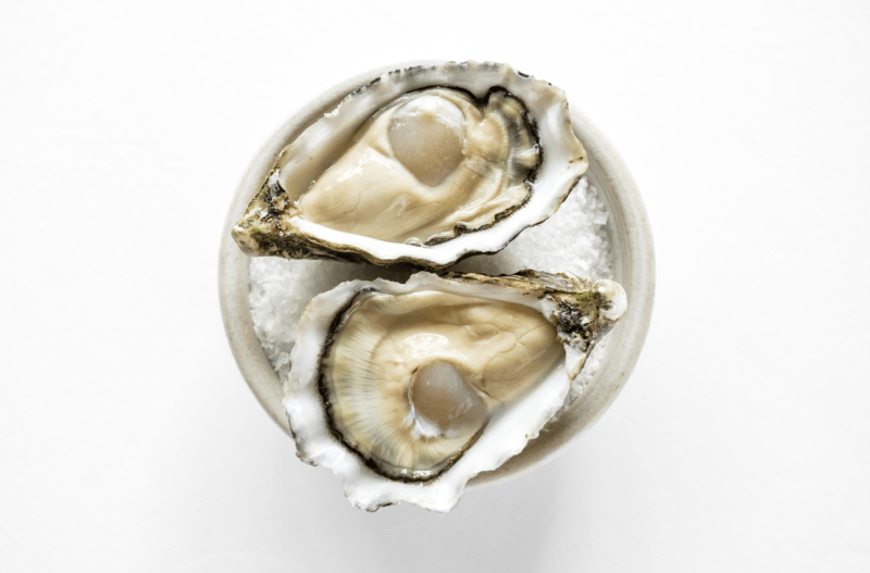 Close-up van verse oesters op een schaal, gepresenteerd op een stijlvolle manier in een restaurant.