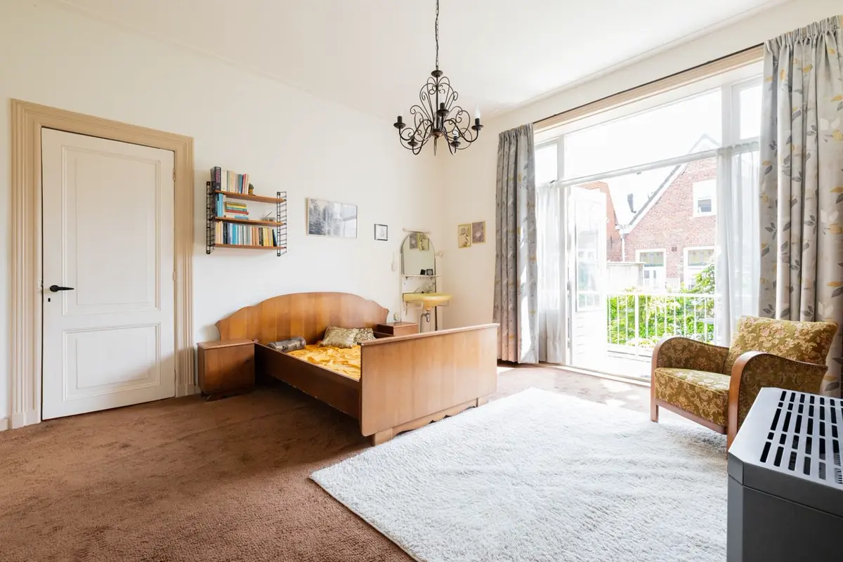 Kamer met bruin tapijt, boekenplank en oude meubels