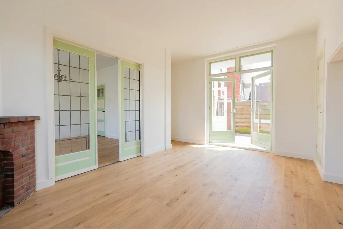 Dezelfde woonkamer digitaal casco opgeleverd met houten vloer en witte wanden