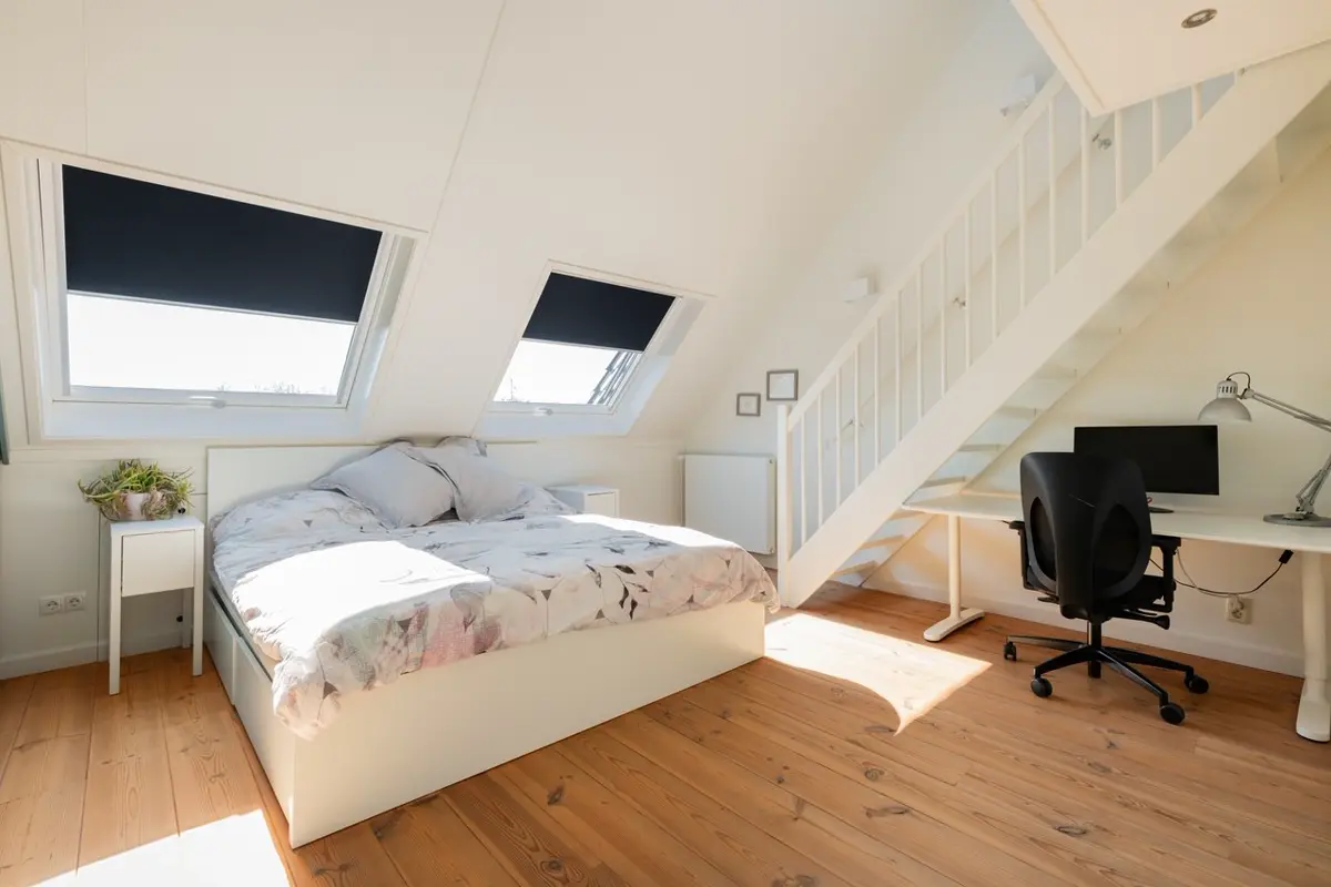 Slaapkamer met bed en bureau onder een schuin dak