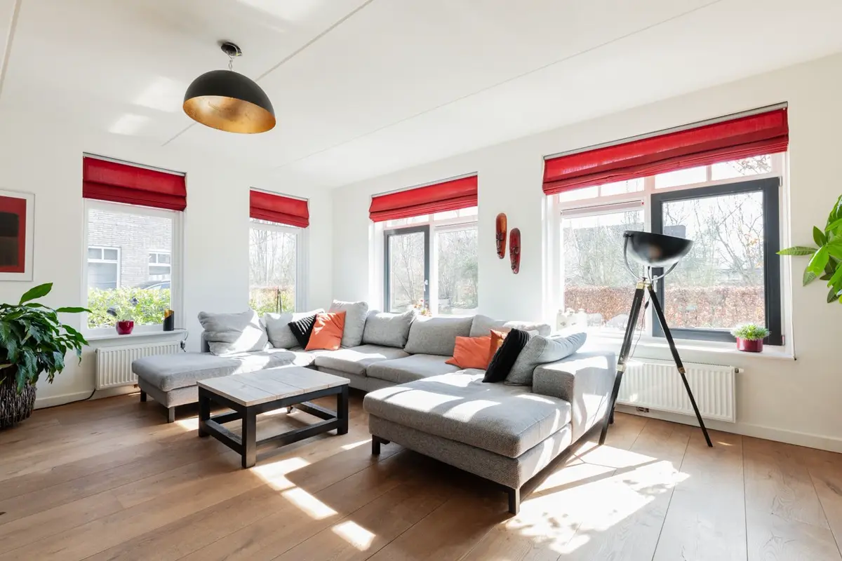 Woonkamer met bestaande inrichting en rode raamdecoratie